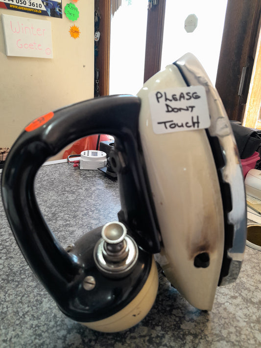 Vintage Tilley Kerosene Iron Model DN250 with a 'Please Don't Touch' sign, displayed on a countertop at Die Skatkis secondhand store.
