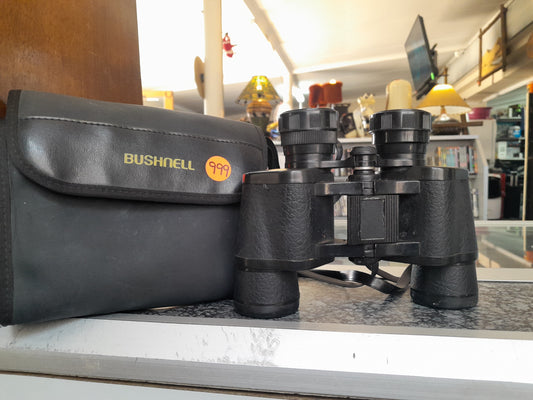 Bushnell 7x35 binoculars with a 140m at 1000m clear view, shown with a black carrying case, available at Die Skatkis secondhand store.
