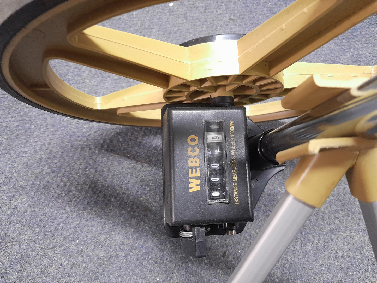 Close-up of Webco Distance Measuring Wheel counter, displaying '0009' with yellow wheel, black rubber edge, and handle, available at Die Skatkis.