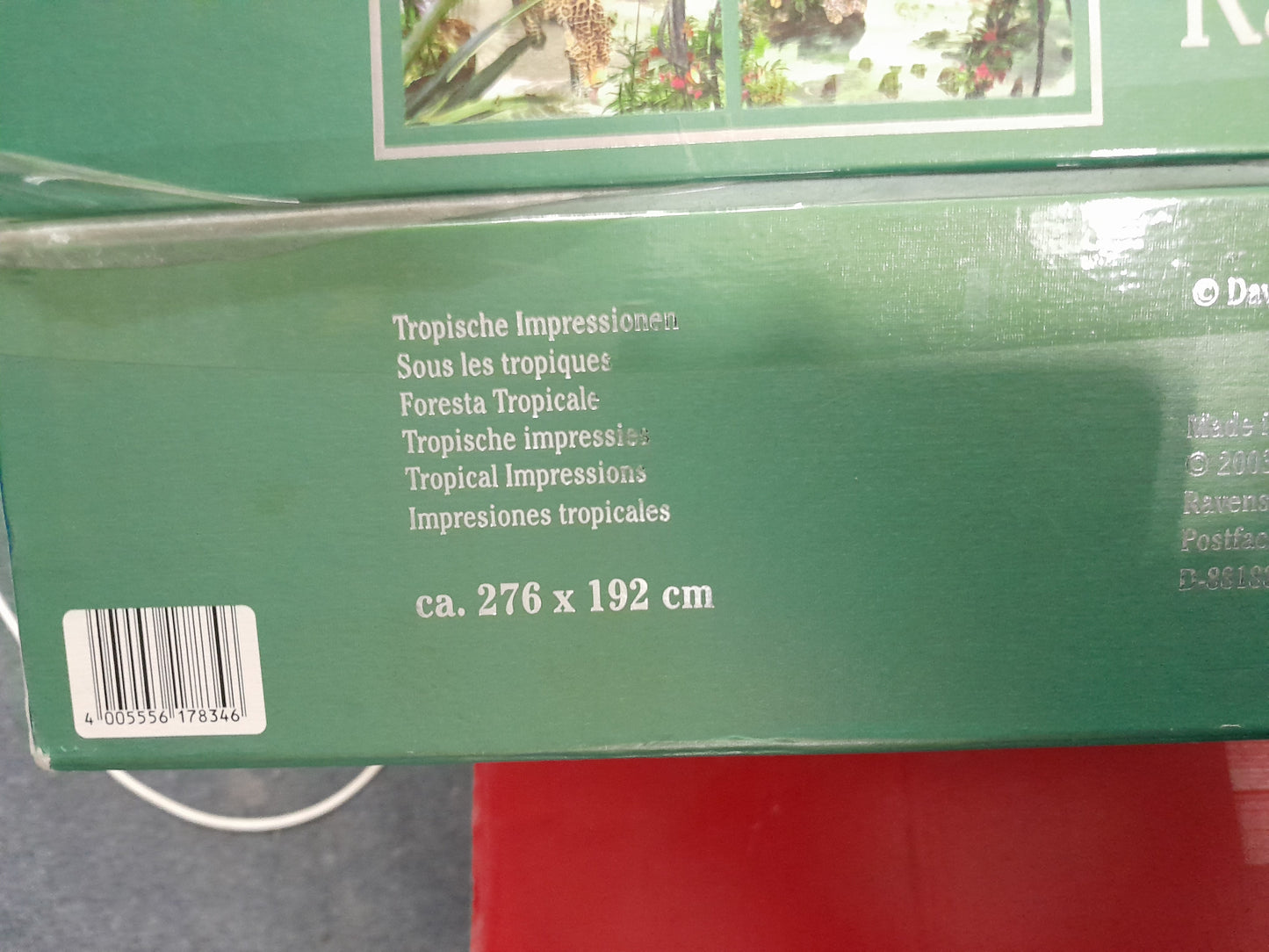 Section of Ravensburger 18000 piece puzzle box showing multilingual titles and dimensions (276 x 192 cm), barcode present, available at Die Skatkis.