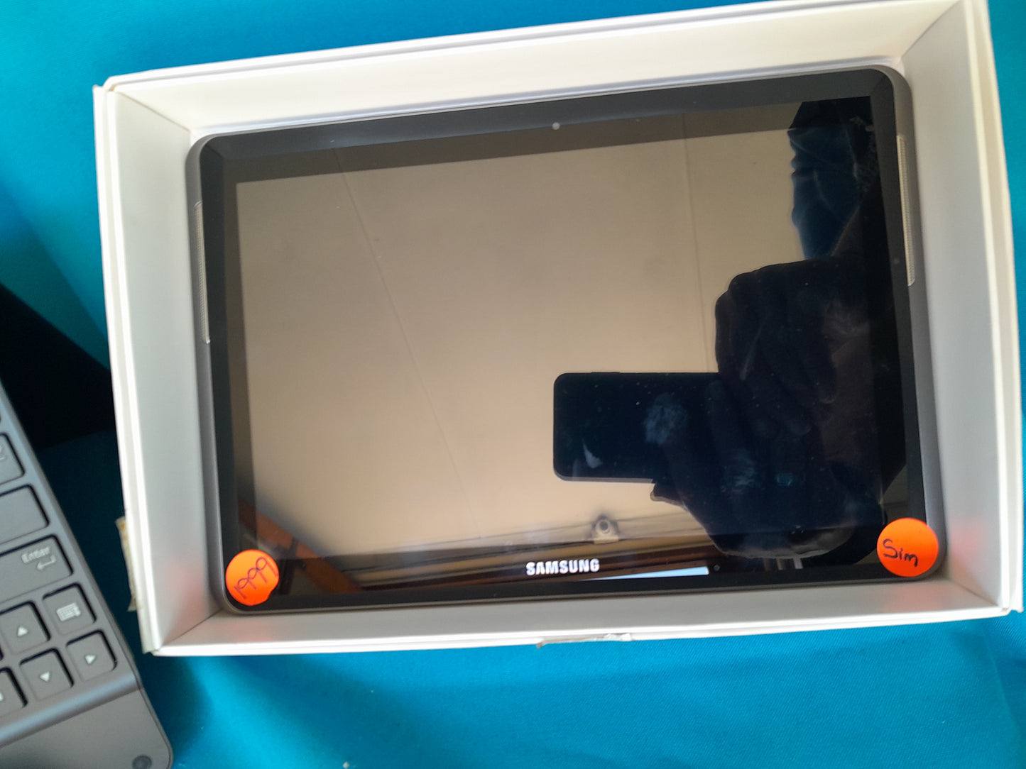 Samsung Galaxy Tab 2 10.1 in original packaging, labeled with orange stickers for 'PPA' and 'Sim,' reflection of person holding phone, available at Die Skatkis.