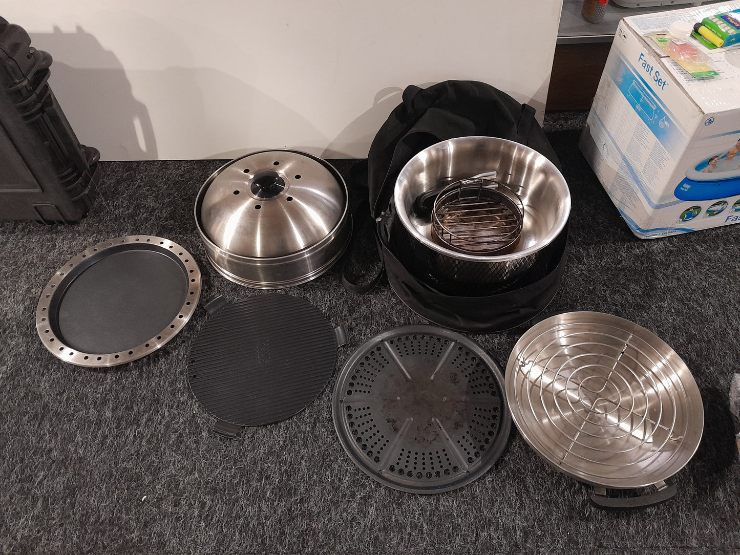 Layout of Cobb kitchen parts including grill, steamer, and cooking trays for outdoor cooking.