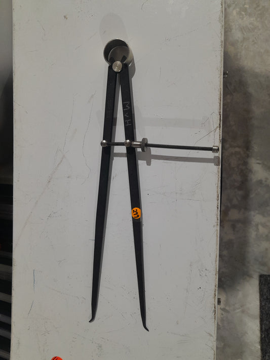 Wing divider compass for measuring distances and scribing arcs in metal and woodwork.