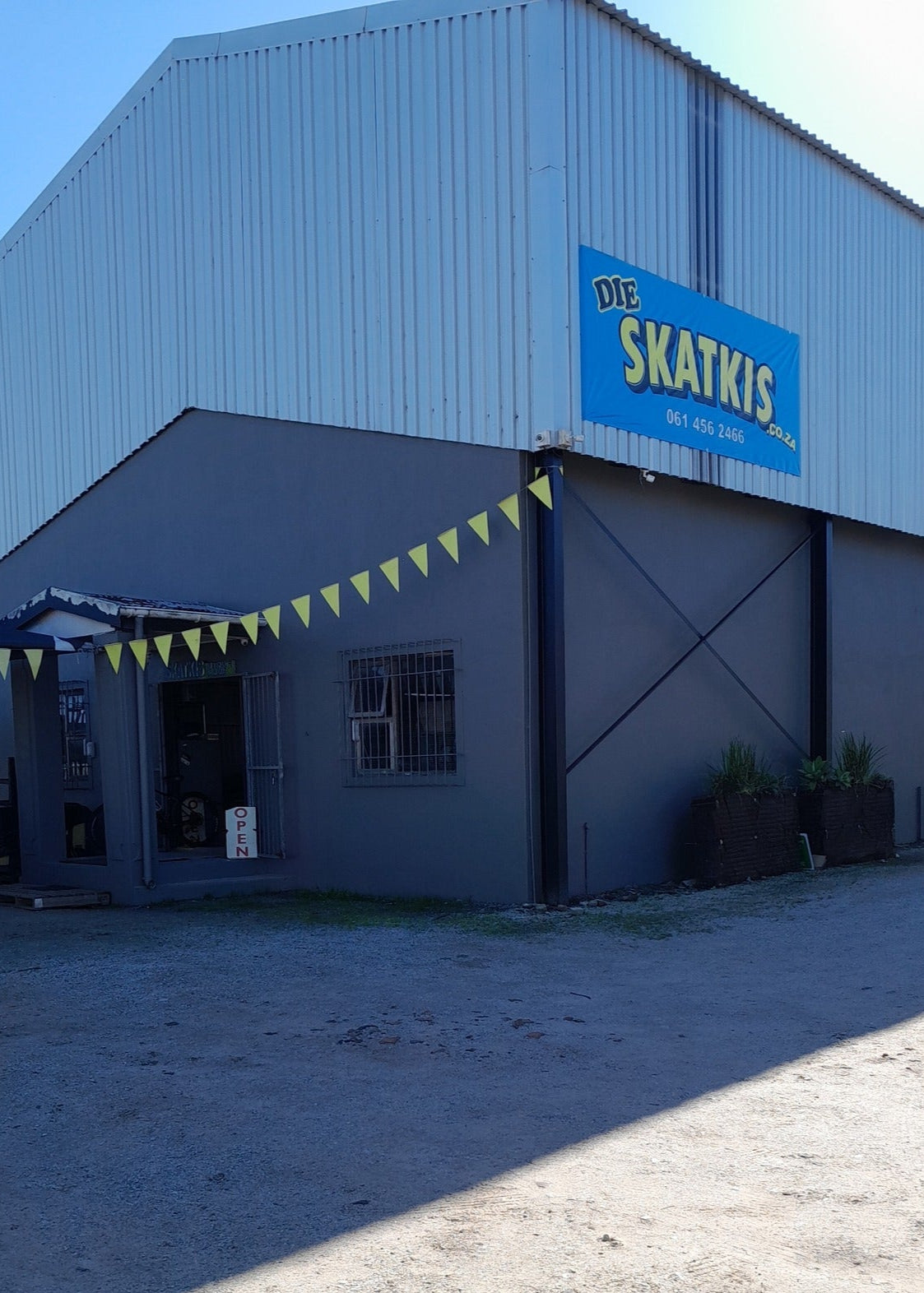 Exterior view of Die Skatkis secondhand shop in George, South Africa, featuring the store's blue and yellow signage and entrance at 8 Trein Street