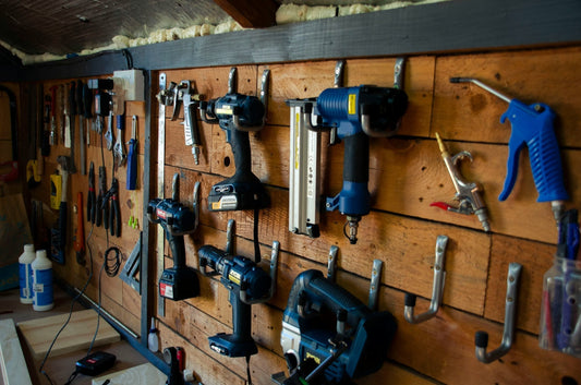 Used power tools neatly displayed on a wooden workshop wall – secondhand drills, nail guns, air compressors, and more available for sale at Die Skatkis online secondhand store South Africa