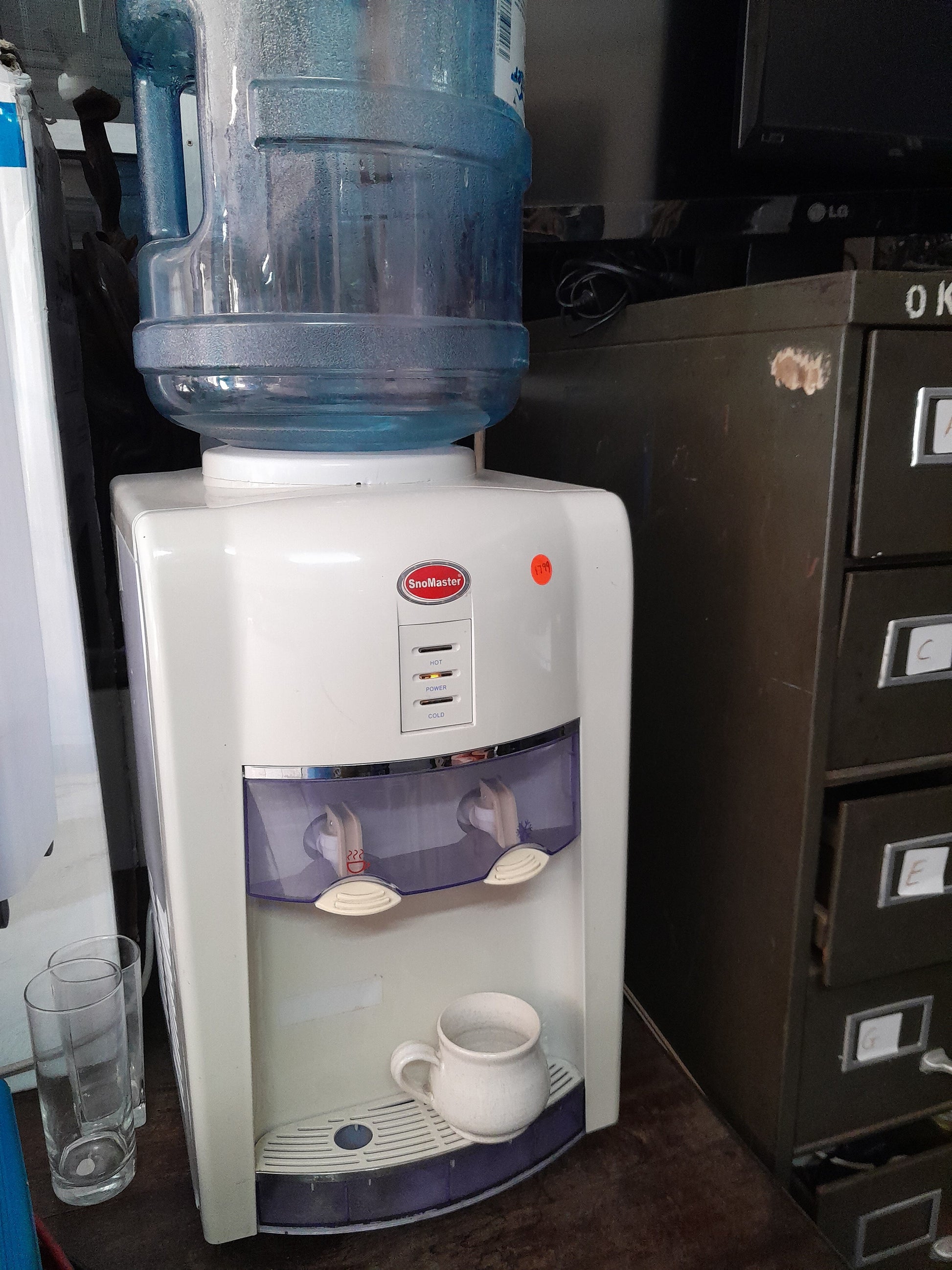 Secondhand SnoMaster water dispenser, hot/cold options with a large blue water bottle on top. Find it at Die Skatkis.