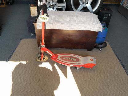 Red Razor E90 electric scooter with a price tag of 999, showcased on beige carpet in a garage, available at Die Skatkis.