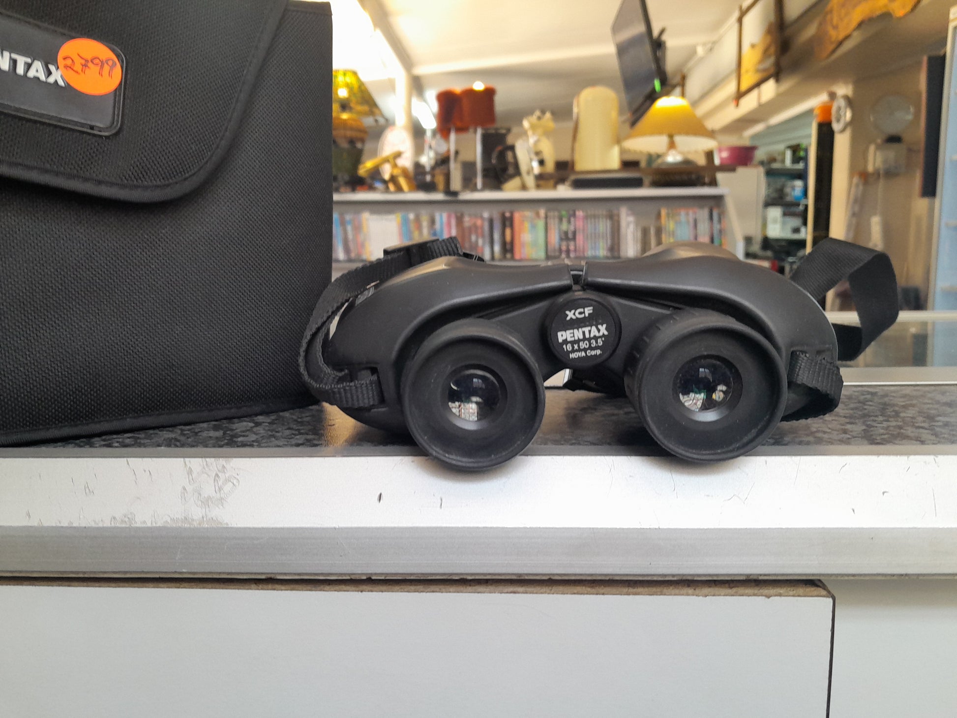 Pentax XCP 16x50 binoculars with 3.5° field of view and black carrying case, price tag attached, available at Die Skatkis secondhand store.