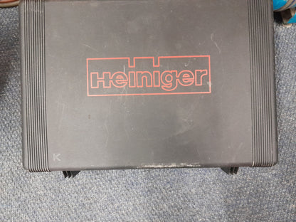 Heiniger electric hand shear in a black textured plastic case with red branding, placed on a blue carpeted floor, available at Die Skatkis.