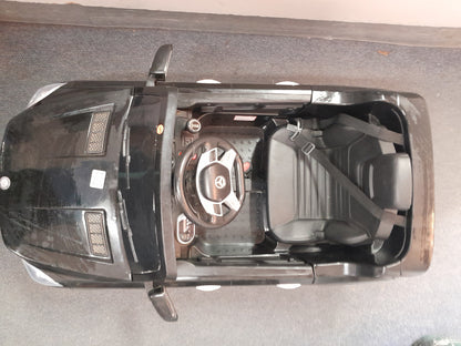 Top-down view of a black Mercedes Benz kiddies car, with a seatbelt and steering wheel, available at Die Skatkis.