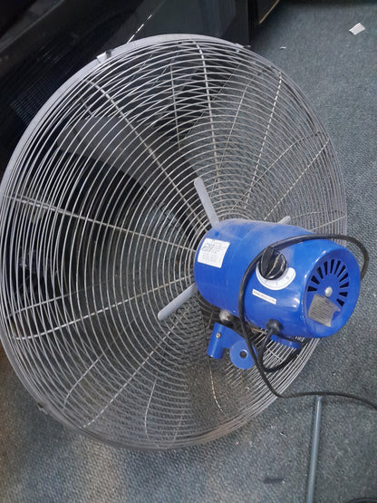 Large AMS industrial fan with blue motor housing and protective metal grille, three blades, placed on a carpeted floor. Available at Die Skatkis.
