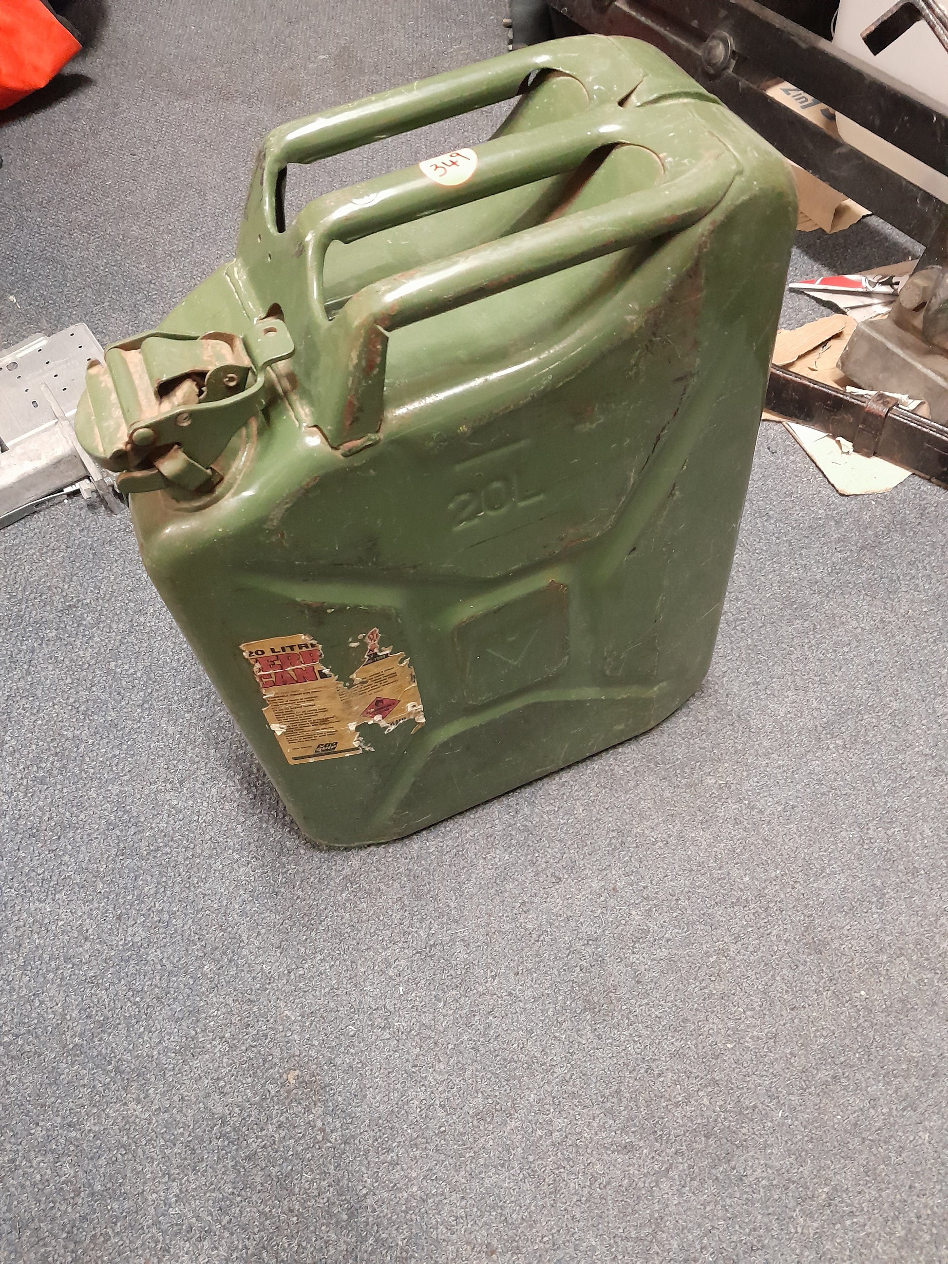 A 20-liter green jerry can on the floor, ideal for storing and transporting liquids like fuel and water. Perfect for outdoor use.