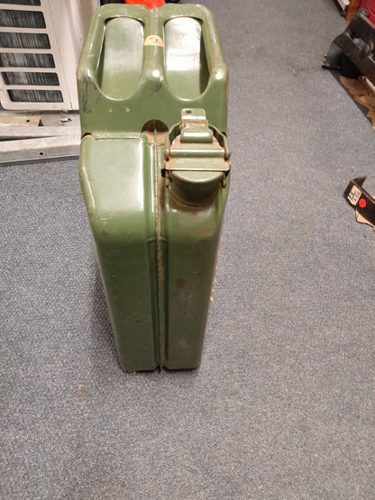 Green 20-liter military-style Jerry canister on the floor, ideal for storing and transporting liquids like fuel and water.
