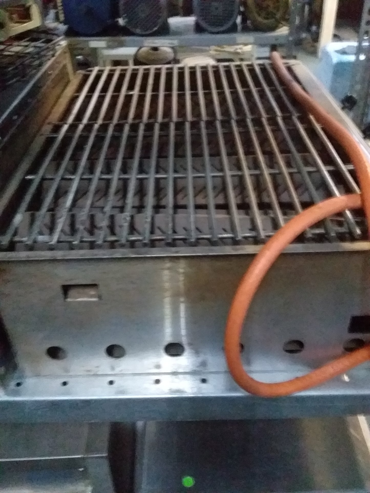 Close-up of metal bars of LK's Gasbraai grill with connected orange gas hose, showcasing durable design for outdoor cooking, available at Die Skatkis.