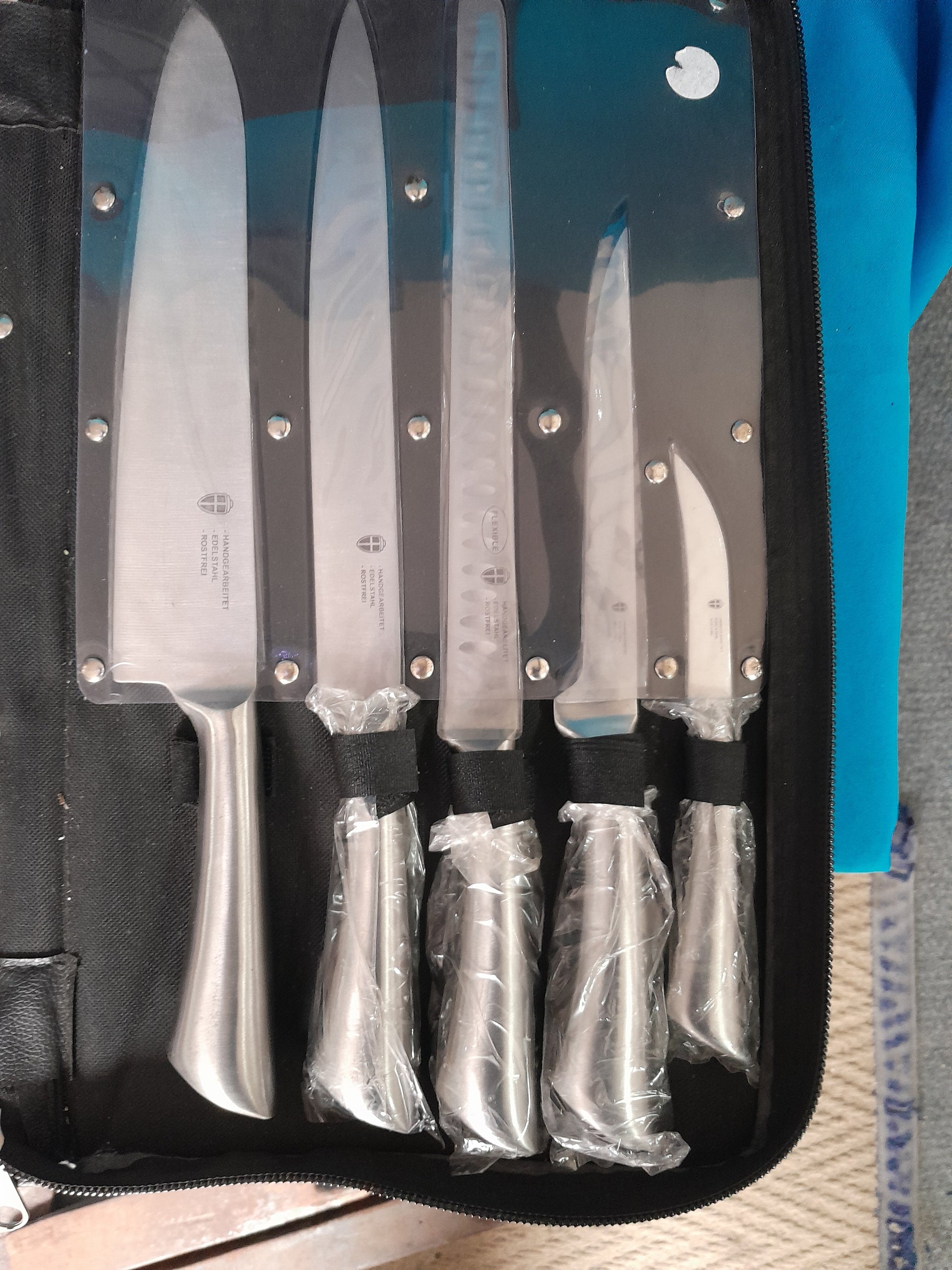 Stainless steel kitchen knives set with a variety of essential tools for chefs, neatly stored in a case.