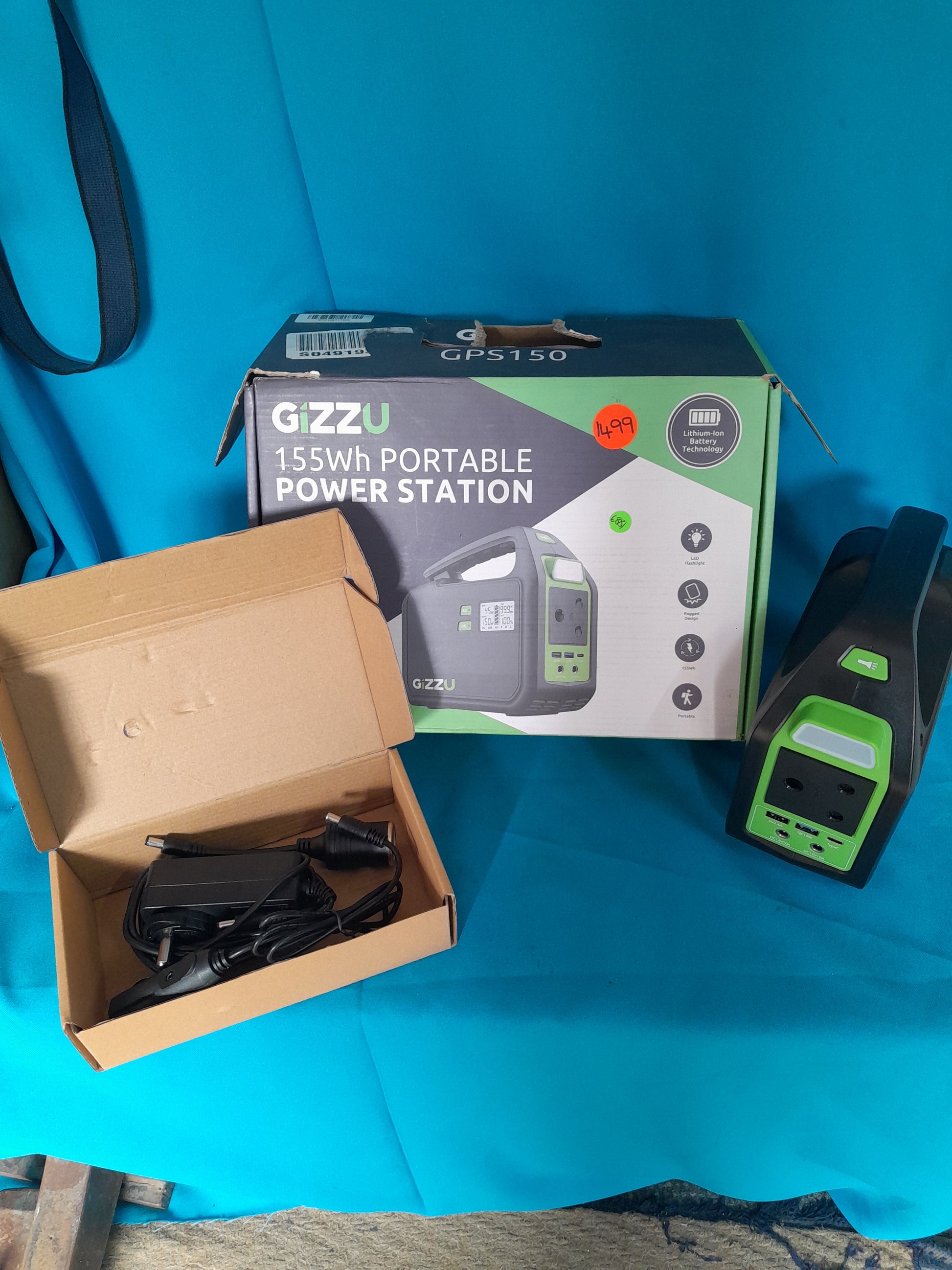 Secondhand Gizzu 155Wh Power Station, highlighting front ports, power adapter, and packaging box, at Die Skatkis.