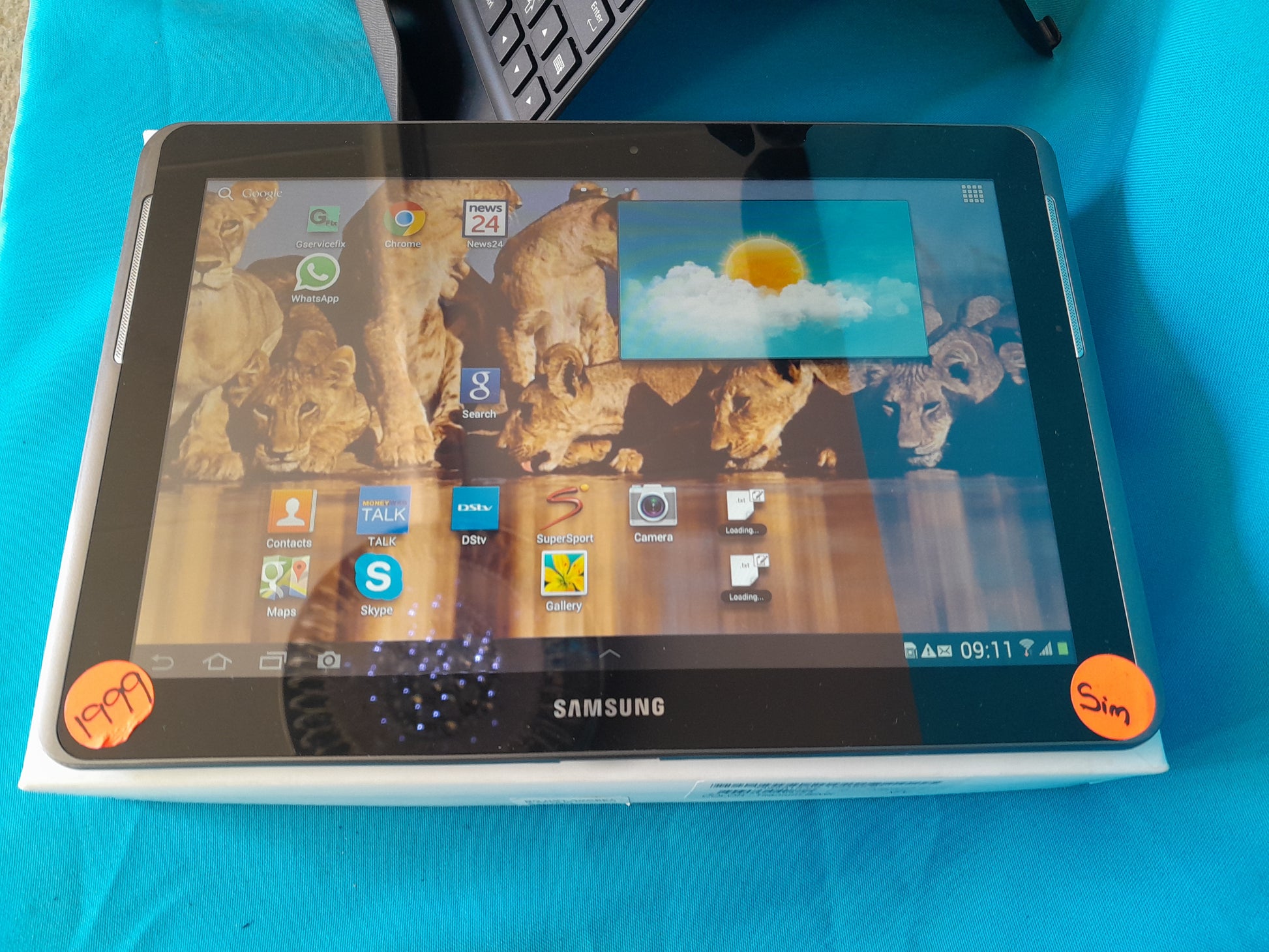 Samsung Galaxy Tab 2 10.1 on blue surface, screen displaying multiple apps including Google Chrome and WhatsApp, available at Die Skatkis secondhand store.