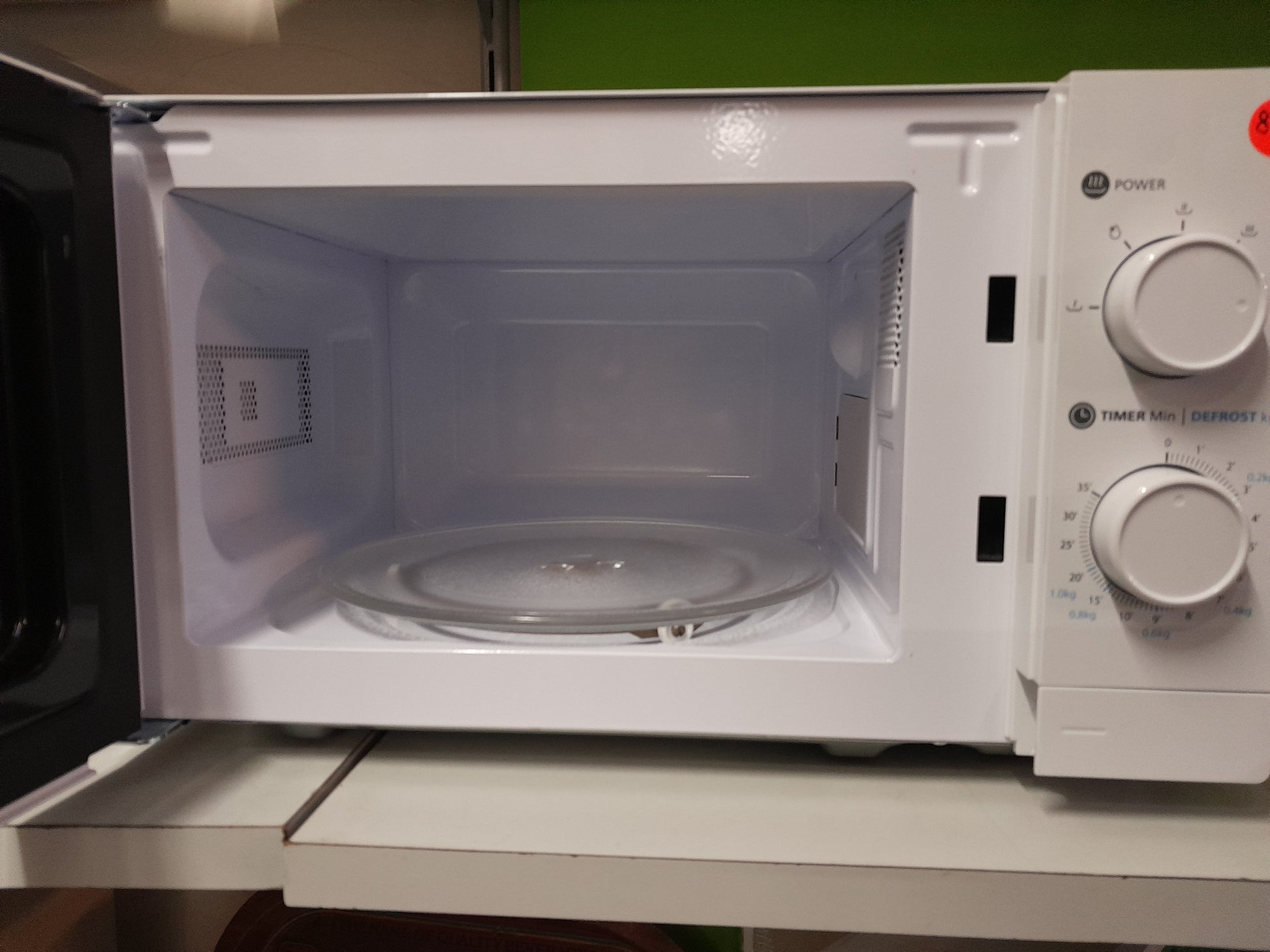 Interior view of a Logik 20 Litre microwave, showcasing the glass turntable and control dials, available at Die Skatkis secondhand store.