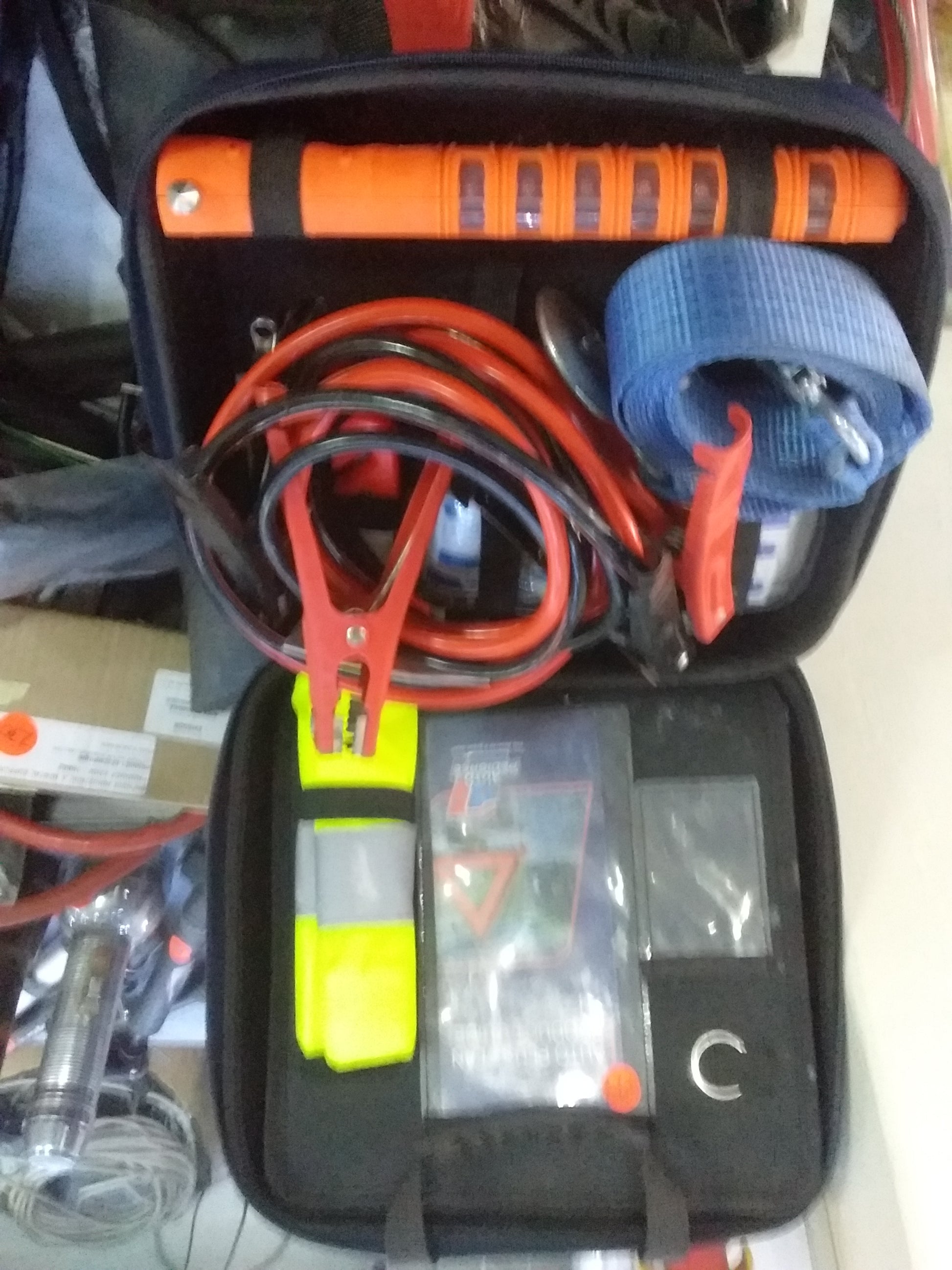 Auto Pedigree Emergency Car Kit with flashlight, jumper cables, tow strap, safety vest, and warning triangle. Available at Die Skatkis
