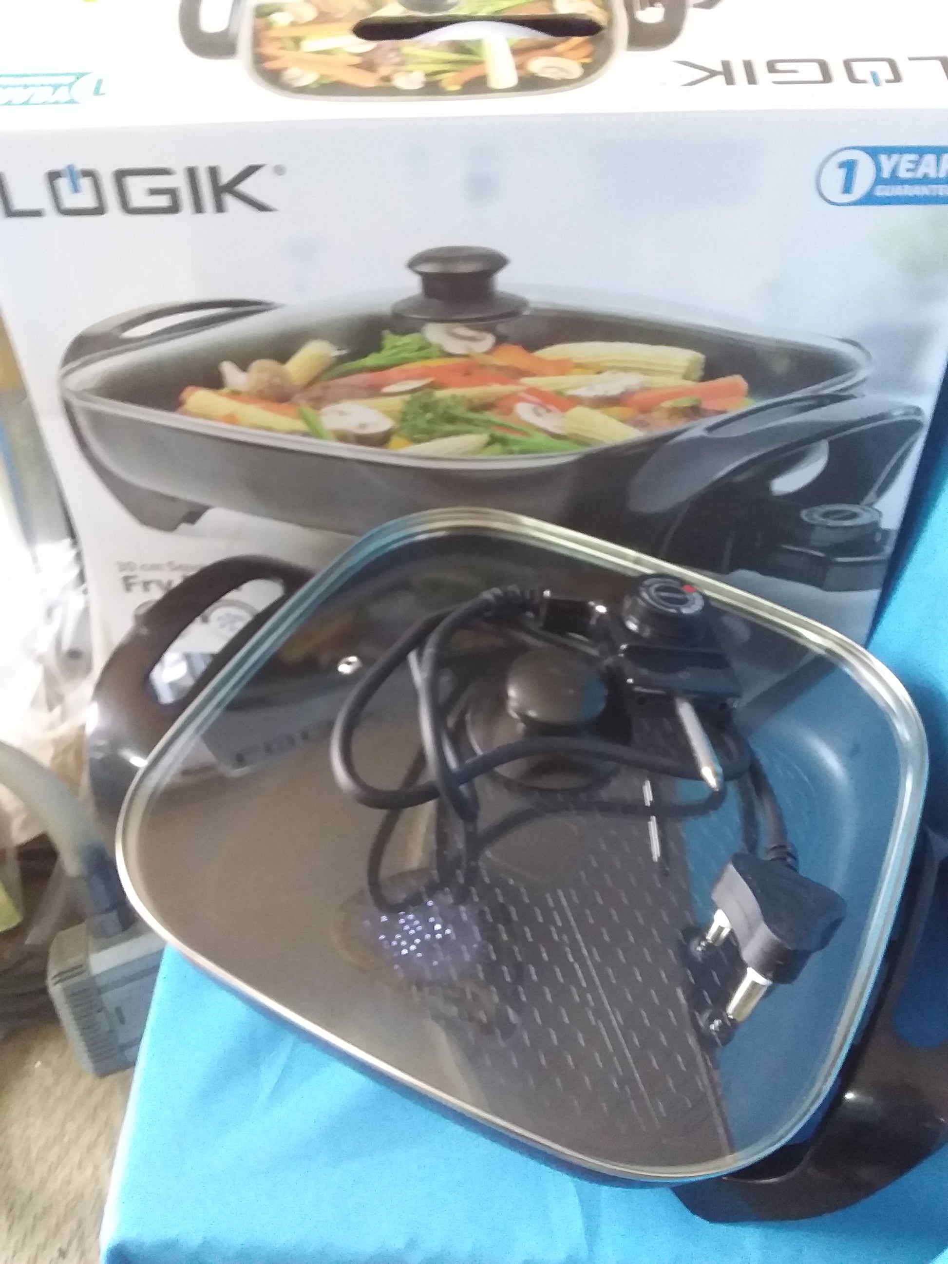 Logik 30cm square fry pan with a glass lid, electric plug, and non-stick surface, shown with original packaging. Available at Die Skatkis.