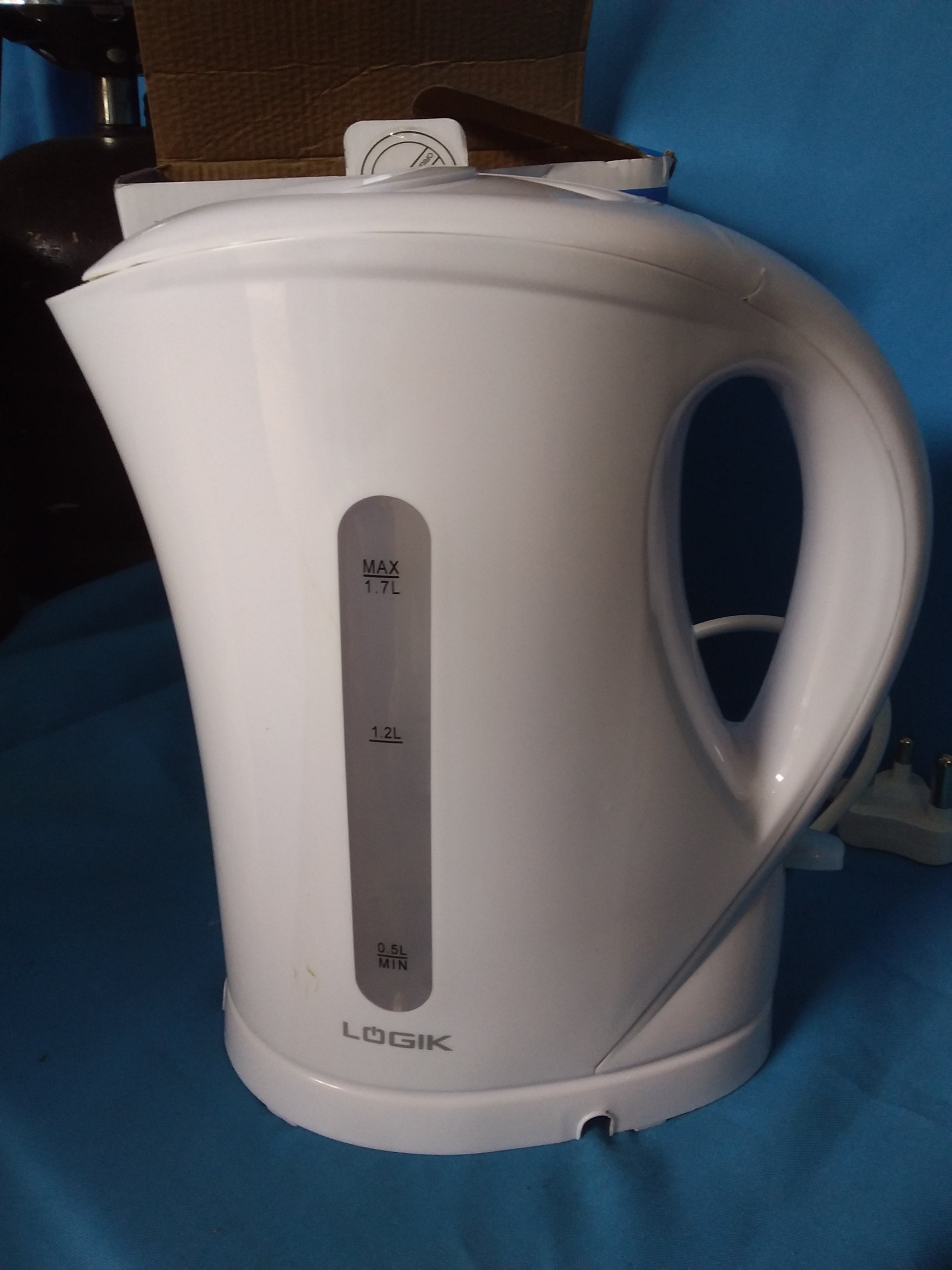 Logik 1.7L white electric kettle with transparent water level indicator, branded LOGIK, displayed on a blue surface. Available at Die Skatkis.