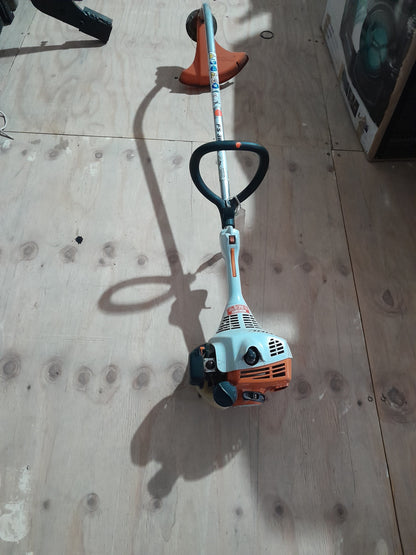 Stihl FS38 weed eater resting on wooden surface, perfect for cutting grass and small weeds.