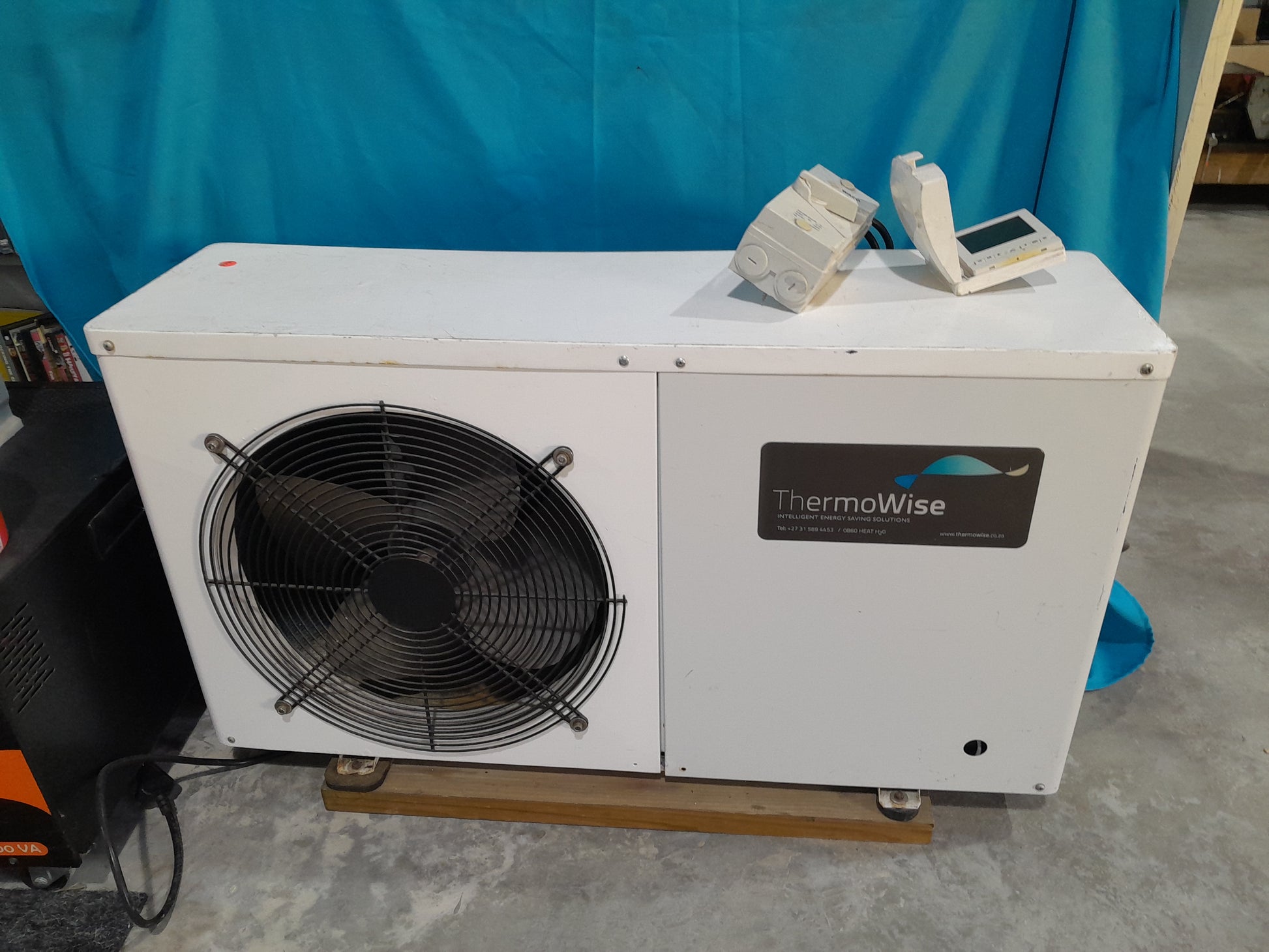 ThermoWise air-conditioning style heat pump with a large fan, set on a wooden base, perfect for water heating systems.